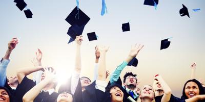 Graduates throwing mortar boards in the air